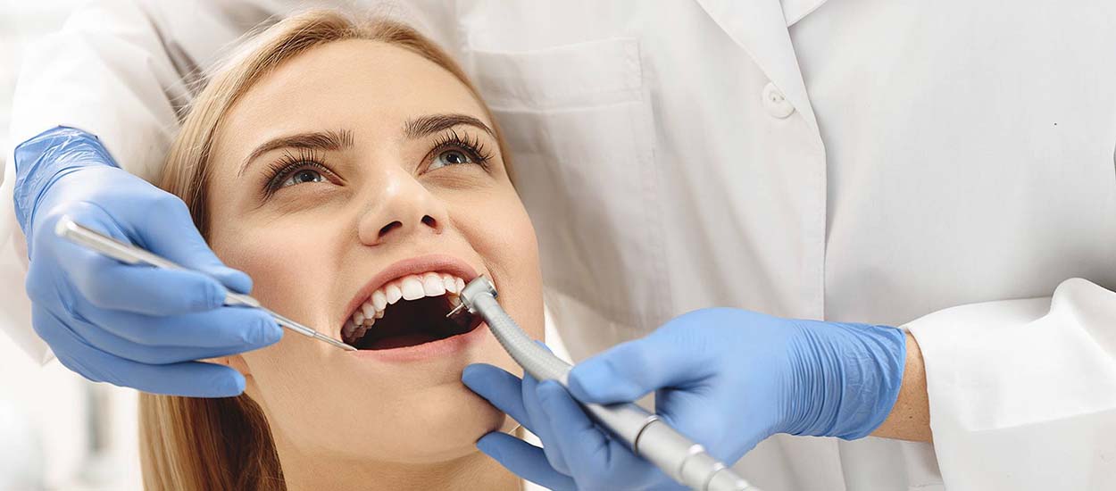 Стоматолог осматривает полость рта девушки, чтобы подготовить ее к имплантации